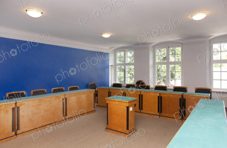 A large meeting room, with desks and chair and central podium, old fashioned decor,…