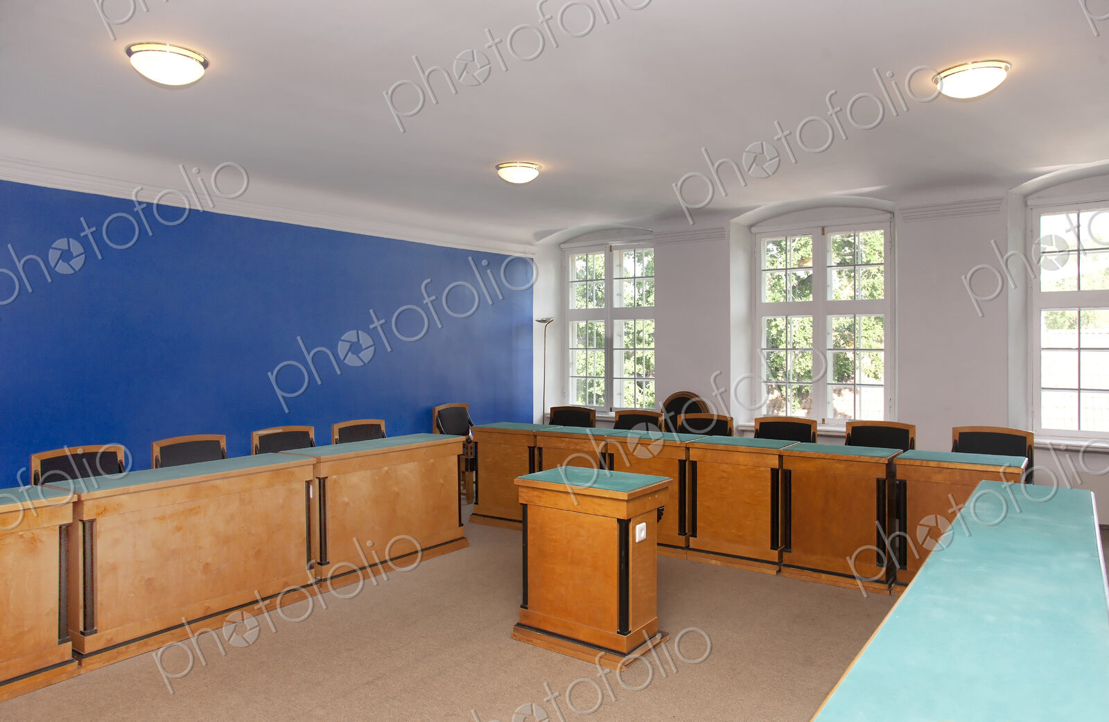 A large meeting room, with desks and chair and central podium, old fashioned decor,…