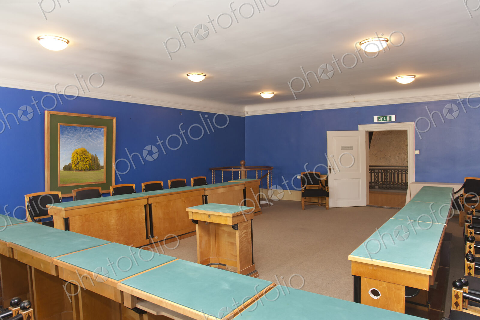 A large meeting room, with desks and chair and central podium, old fashioned decor,…