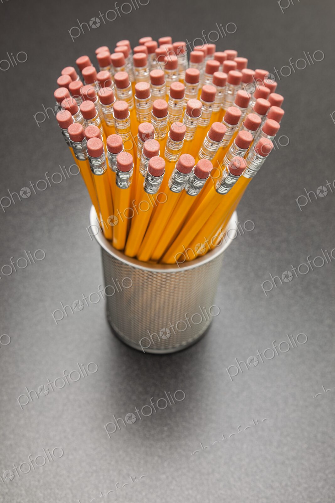 A large number of yellow No. 2 pencils in cup on desk, view from above