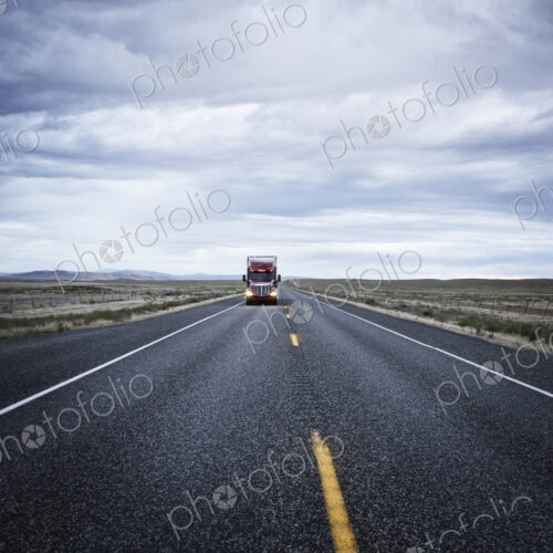 A large red commercial truck on the highway, in the distance A large red commercial truck on the highway, in the distance