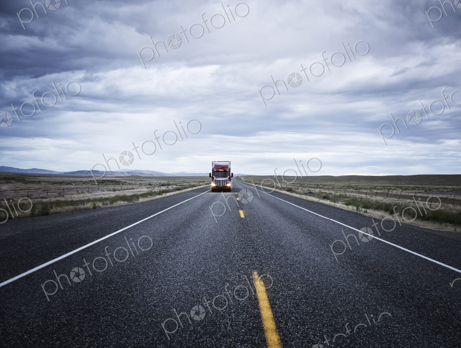 A large red commercial truck on the highway, in the distance
