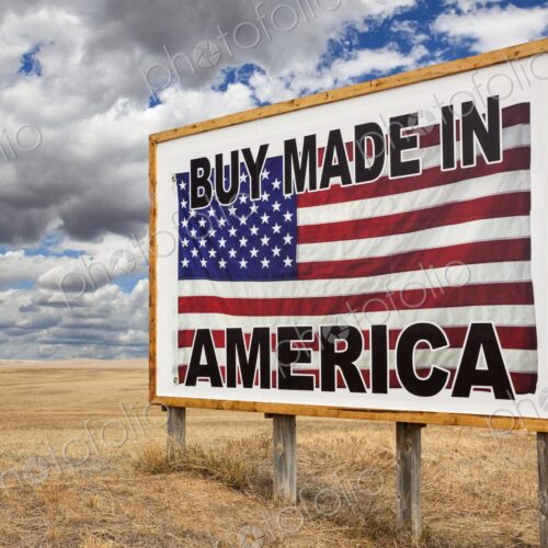 A large roadside billboard with an American flag reading Buy Made in America stands on…