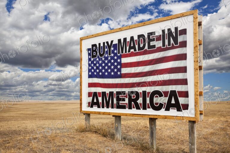 A large roadside billboard with an American flag reading Buy Made in America stands on…