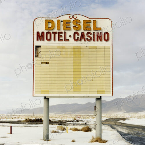 A large roadside sign in a flat landscape with light snow. Mountain range. Diesel and… A large roadside sign in a flat landscape with light snow. Mountain range. Diesel and…