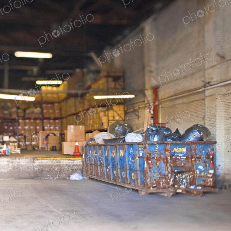 A large storage facility with loading bay, racks of boxes and large refuse skip
