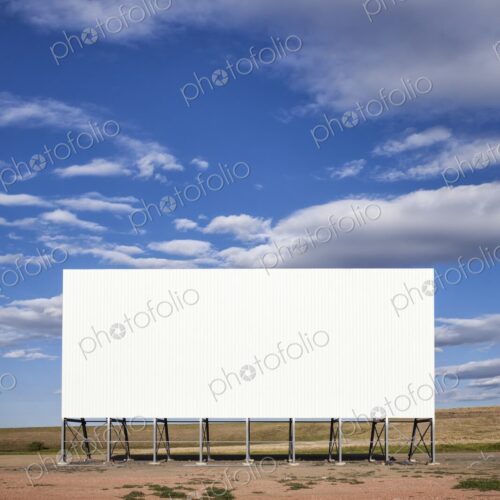 A large white drive in movie screen stands on the prairie beneath a wide blue sky with… A large white drive in movie screen stands on the prairie beneath a wide blue sky with…