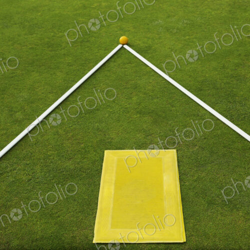 A lawn bowls green edge, a yellow player's mat to stand on and two white lengths of… A lawn bowls green edge, a yellow player's mat to stand on and two white lengths of…