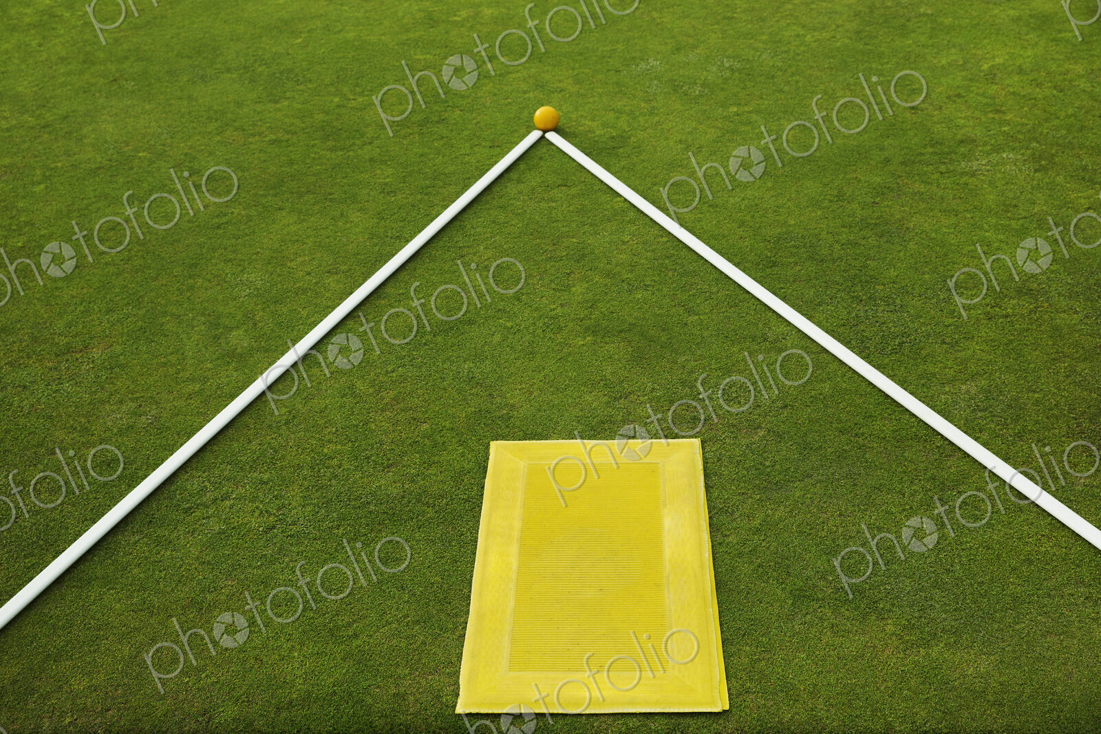 A lawn bowls green edge, a yellow player’s mat to stand on and two white lengths of…