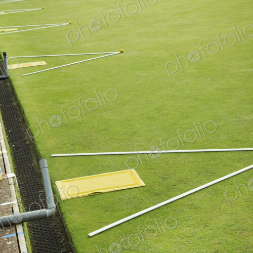 A lawn bowls green edge, a yellow player's mat to stand on and two white lengths of… A lawn bowls green edge, a yellow player's mat to stand on and two white lengths of…