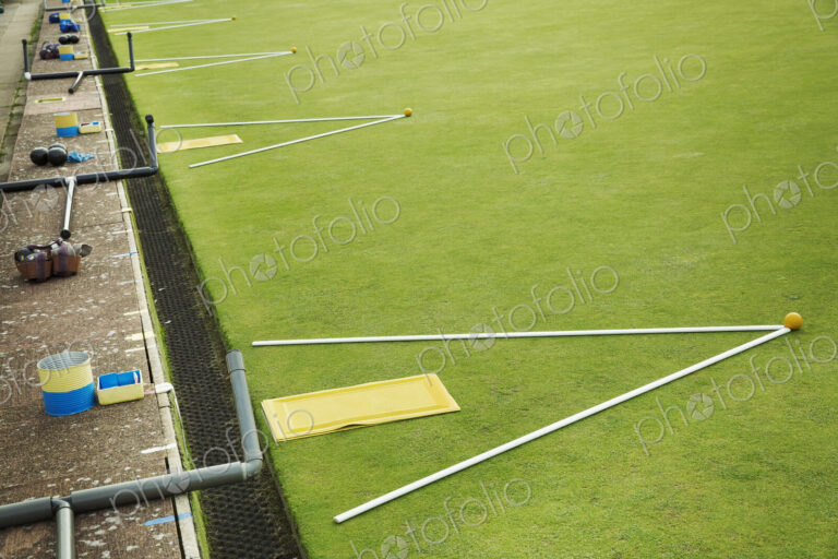 A lawn bowls green edge, a yellow player's mat to stand on and two white lengths of…