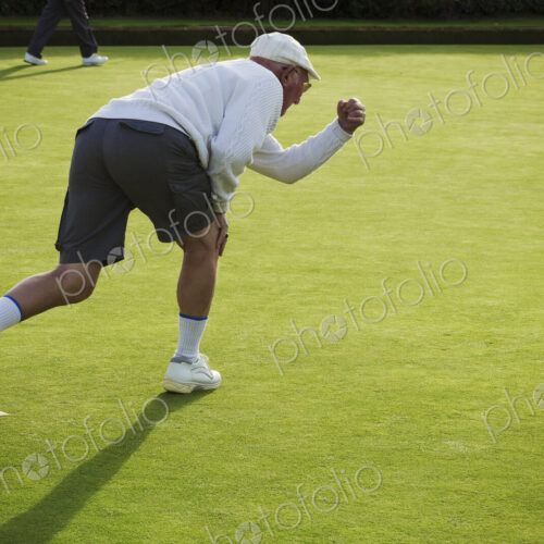 A lawn bowls player standing on a small yellow mat preparing to deliver a bowl down… A lawn bowls player standing on a small yellow mat preparing to deliver a bowl down…
