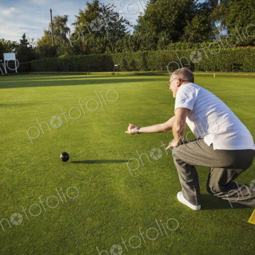A lawn bowls player standing on a small yellow mat preparing to deliver a bowl down… A lawn bowls player standing on a small yellow mat preparing to deliver a bowl down…