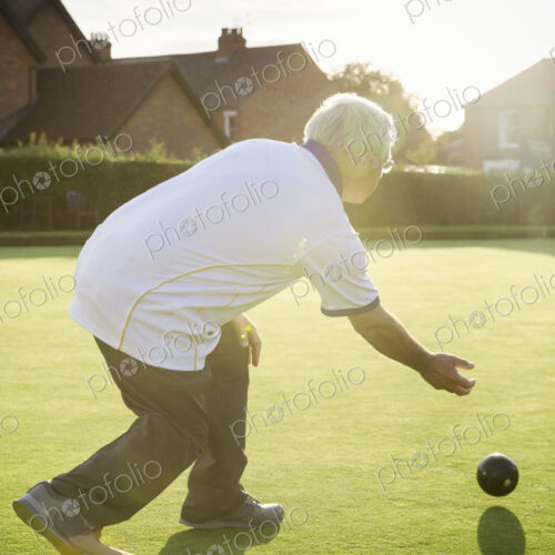 A lawn bowls player standing on a small yellow mat preparing to deliver a bowl down… A lawn bowls player standing on a small yellow mat preparing to deliver a bowl down…