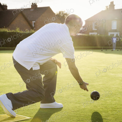 A lawn bowls player standing on a small yellow mat preparing to deliver a bowl down… A lawn bowls player standing on a small yellow mat preparing to deliver a bowl down…