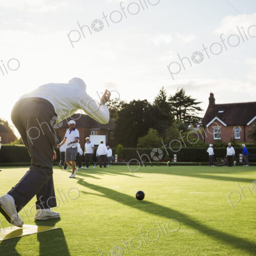 A lawn bowls player standing on a small yellow mat preparing to deliver a bowl down… A lawn bowls player standing on a small yellow mat preparing to deliver a bowl down…