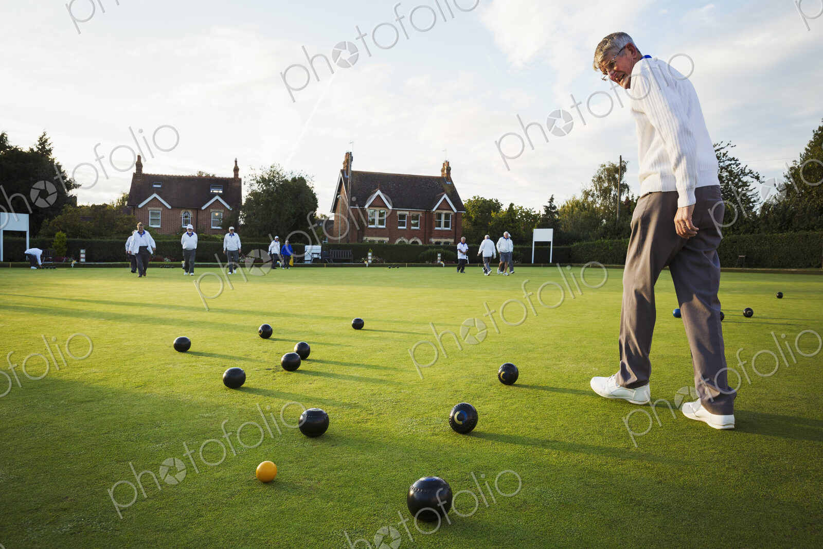 A lawn bowls player walking across the green, the playing surface, at an end with…