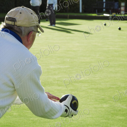 A lawn bowls player wearing a glove, holding and preparing to deliver a bowl down the… A lawn bowls player wearing a glove, holding and preparing to deliver a bowl down the…