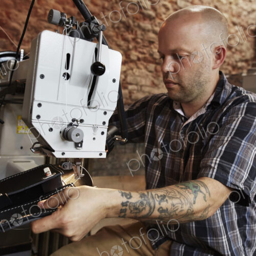 A leather worker, craftsman using an industrial sewing machine on leather material,… A leather worker, craftsman using an industrial sewing machine on leather material,…