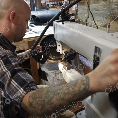 A leather worker, craftsman using an industrial sewing machine on leather material,… A leather worker, craftsman using an industrial sewing machine on leather material,…