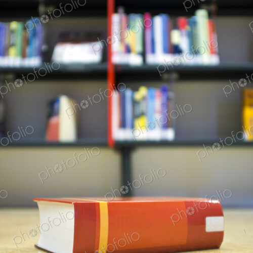 A library book on the floor in front of a bookshelf in a public library, space on the… A library book on the floor in front of a bookshelf in a public library, space on the…