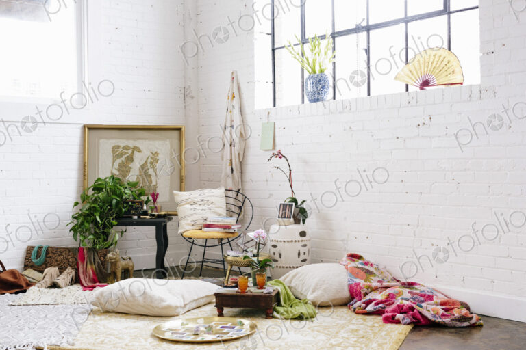 A light airy room with whitewashed walls. Cushions and possessions scattered across…