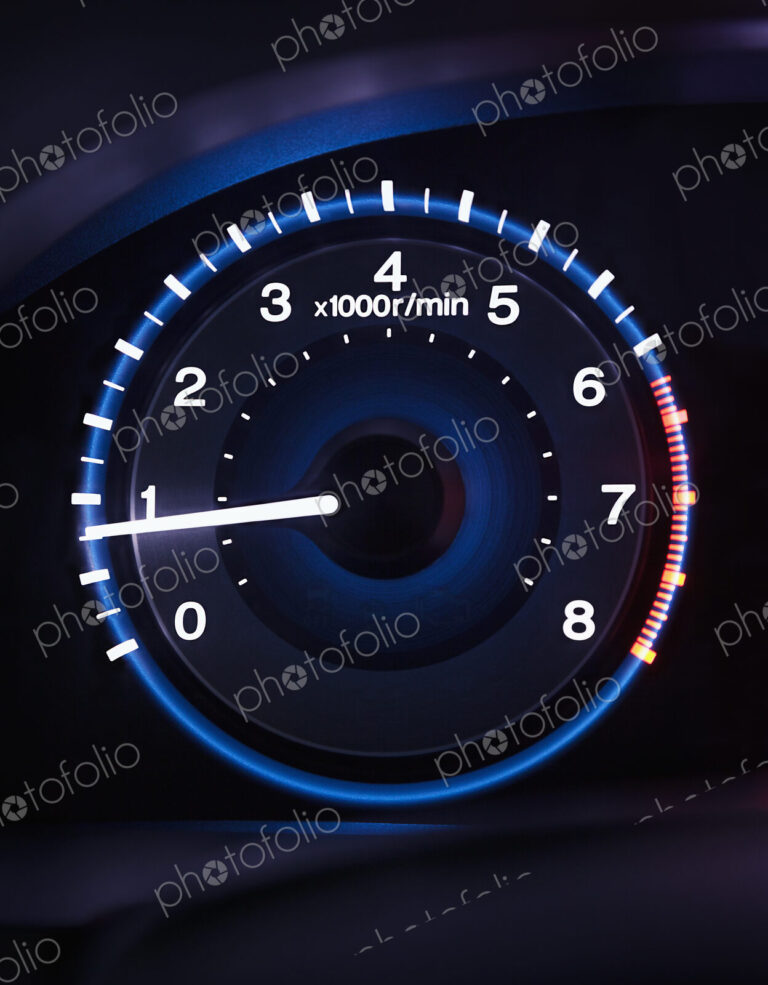 A lit up car dashboard guage, rev counter.