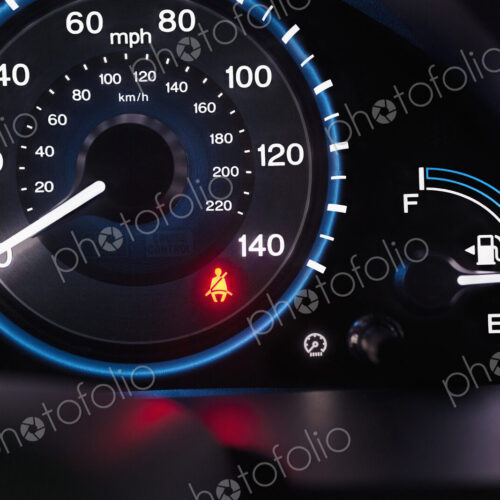 A lit up car dashboard, mph speed dial, in miles and kilometres, fuel guard and a red…