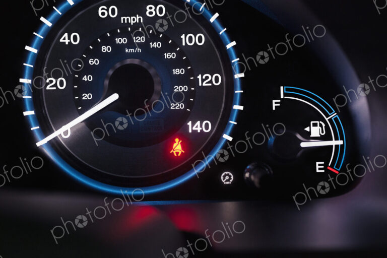 A lit up car dashboard, mph speed dial, in miles and kilometres, fuel guard and a red…