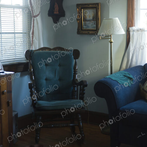 A living room in a house, window with curtains, floor lamp and blue padded rocking… A living room in a house, window with curtains, floor lamp and blue padded rocking…