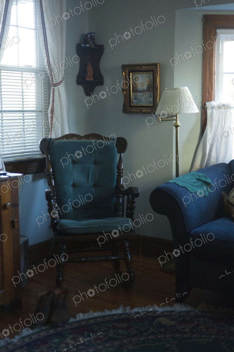 A living room in a house, window with curtains, floor lamp and blue padded rocking…