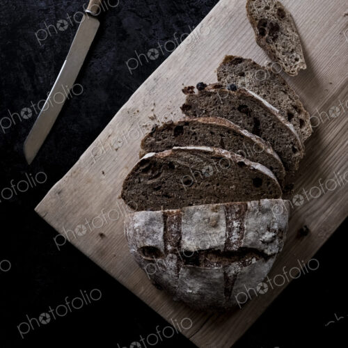 A loaf of fresh sliced brown bread on a bread board and a sharp knife A loaf of fresh sliced brown bread on a bread board and a sharp knife
