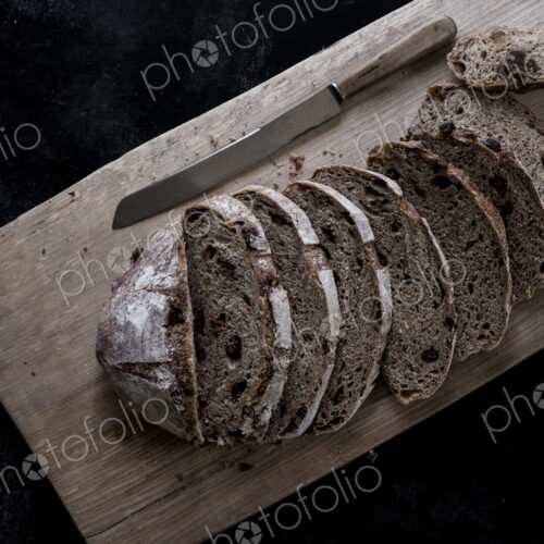 A loaf of fresh sliced brown bread on a bread board and a sharp knife A loaf of fresh sliced brown bread on a bread board and a sharp knife