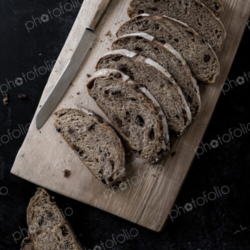 A loaf of fresh sliced brown bread on a bread board and a sharp knife A loaf of fresh sliced brown bread on a bread board and a sharp knife