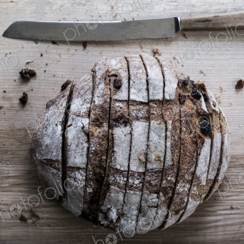 A loaf of fresh sliced brown bread on a bread board and a sharp knife A loaf of fresh sliced brown bread on a bread board and a sharp knife