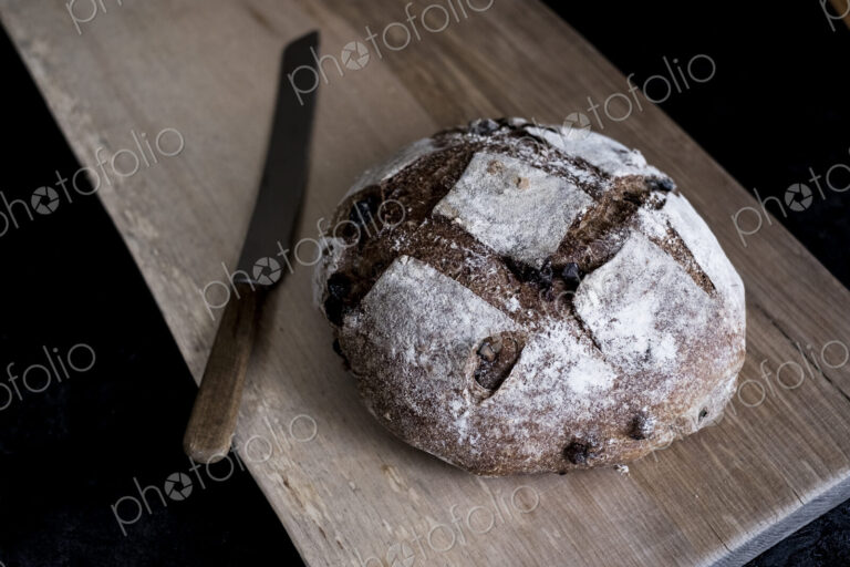 A loaf of freshly baked brown bread with a thick crust on a bread board.