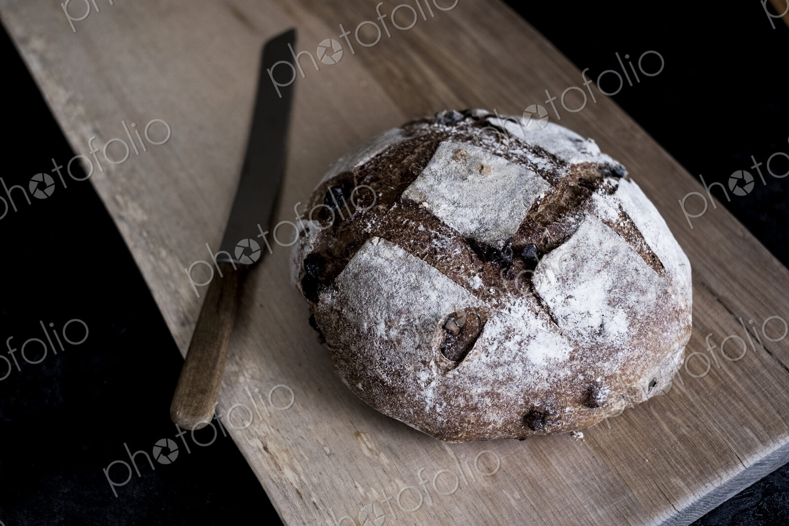 A loaf of freshly baked brown bread with a thick crust on a bread board.