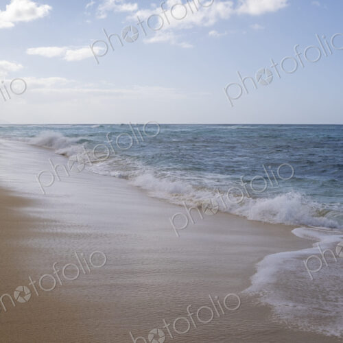 A lone person walks along Waimea Bay Beach, North Shore, waves breaking on the beach. A lone person walks along Waimea Bay Beach, North Shore, waves breaking on the beach.