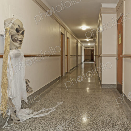 A long corridor in a building, a ghost costume hanging from a wall hook.
