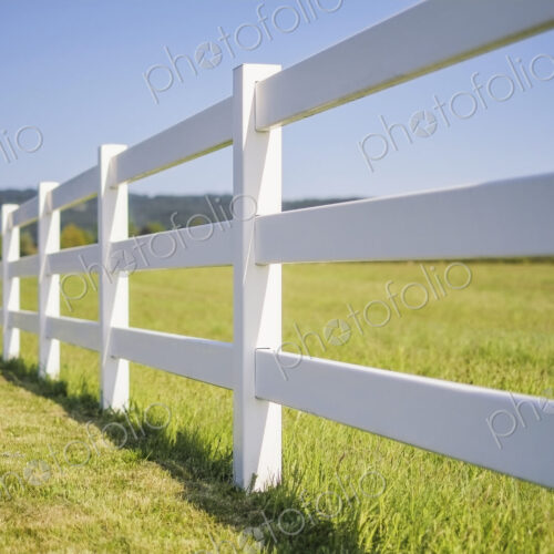A long white farm fence in countryside surrounding pasture, Hockinson, Washington, USA. A long white farm fence in countryside surrounding pasture, Hockinson, Washington, USA.