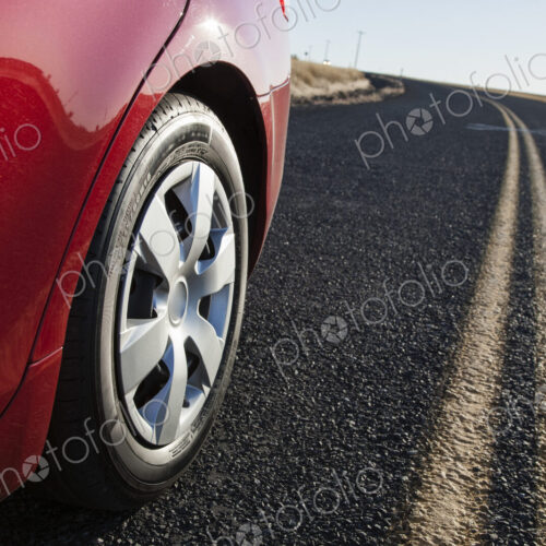 A low angle view of a rear tire on a car as it drives on the hghway. A low angle view of a rear tire on a car as it drives on the hghway.