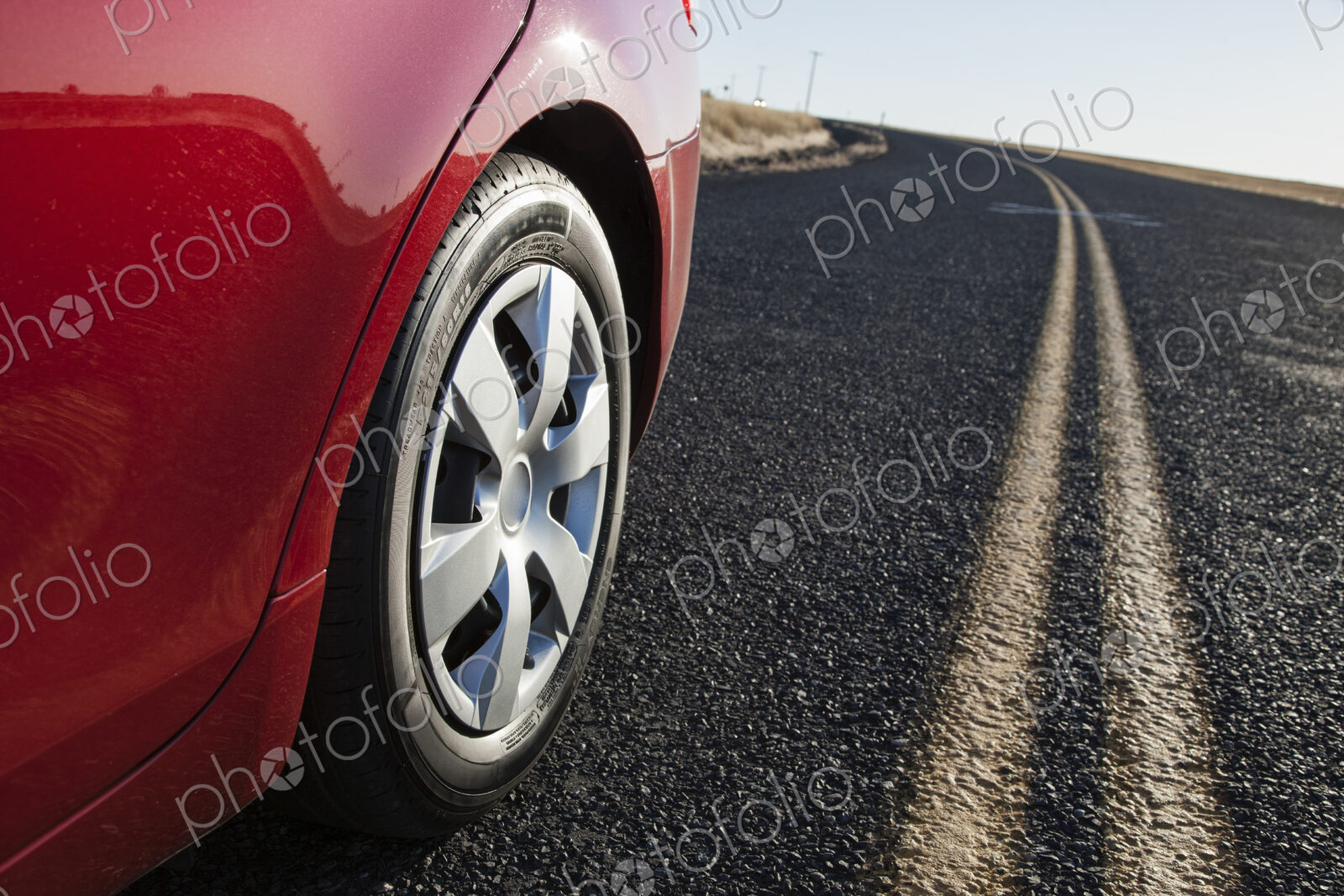 A low angle view of a rear tire on a car as it drives on the hghway.