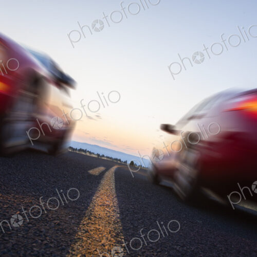 A low angle view of two cars blurred and passing each other going opposite ways on a…