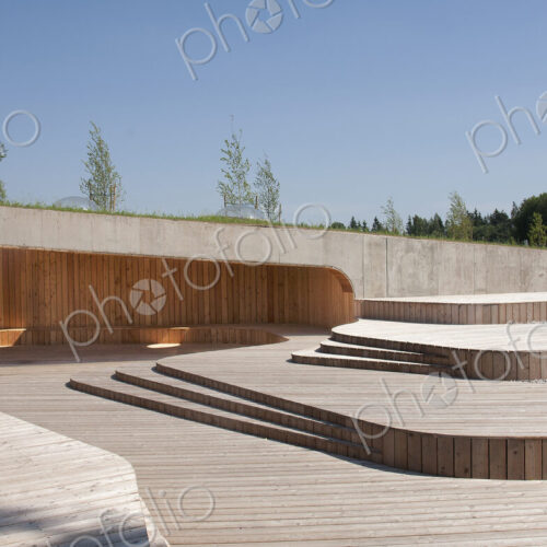 A low profile building at a public museum park with natural wooden panels and decking.