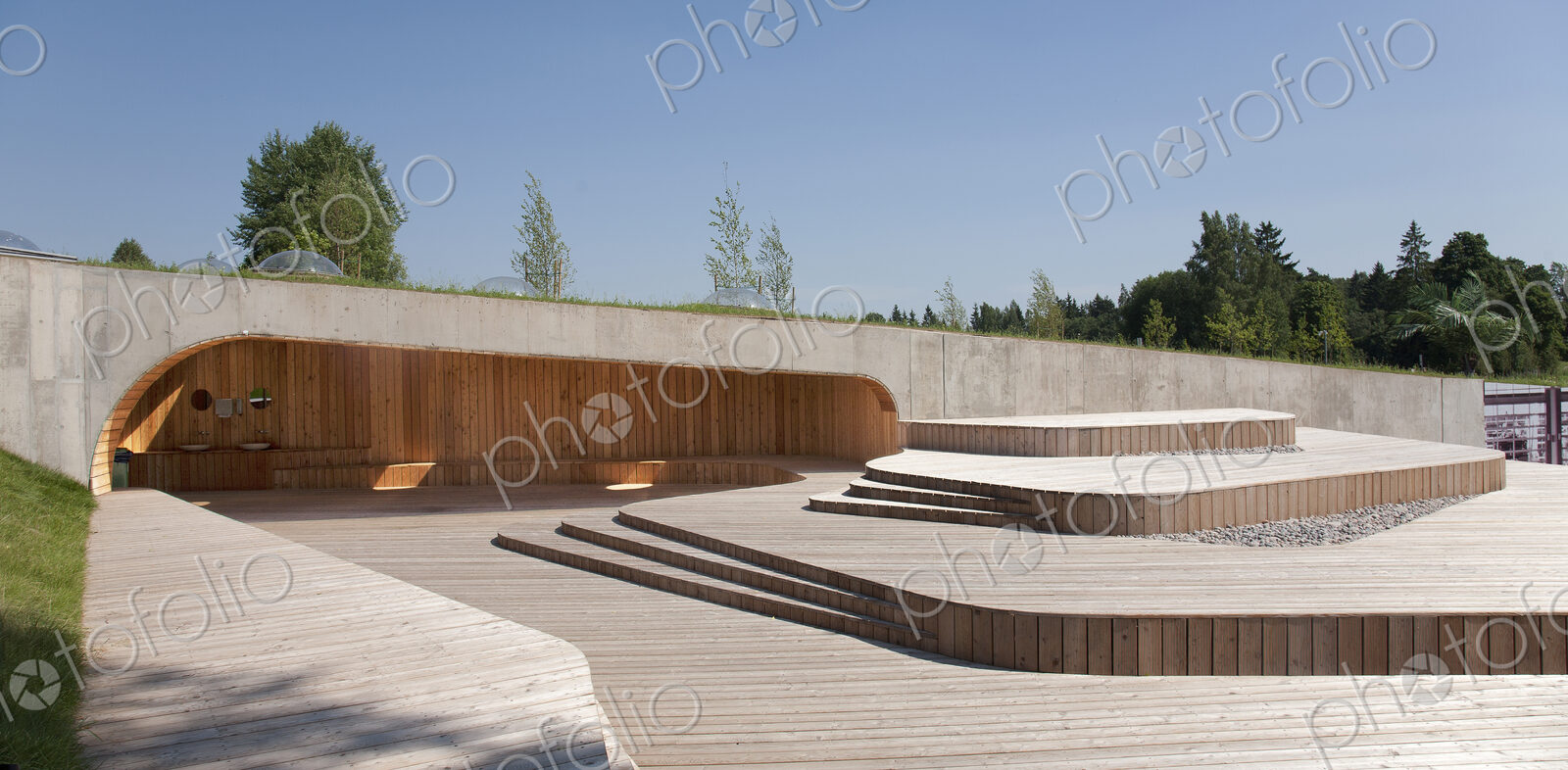 A low profile building at a public museum park with natural wooden panels and decking.
