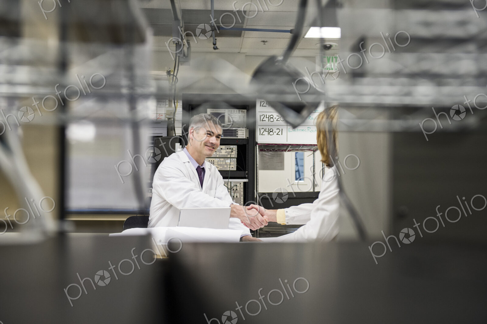 A male caucasian technician greeting a female coworker in a technical research and…
