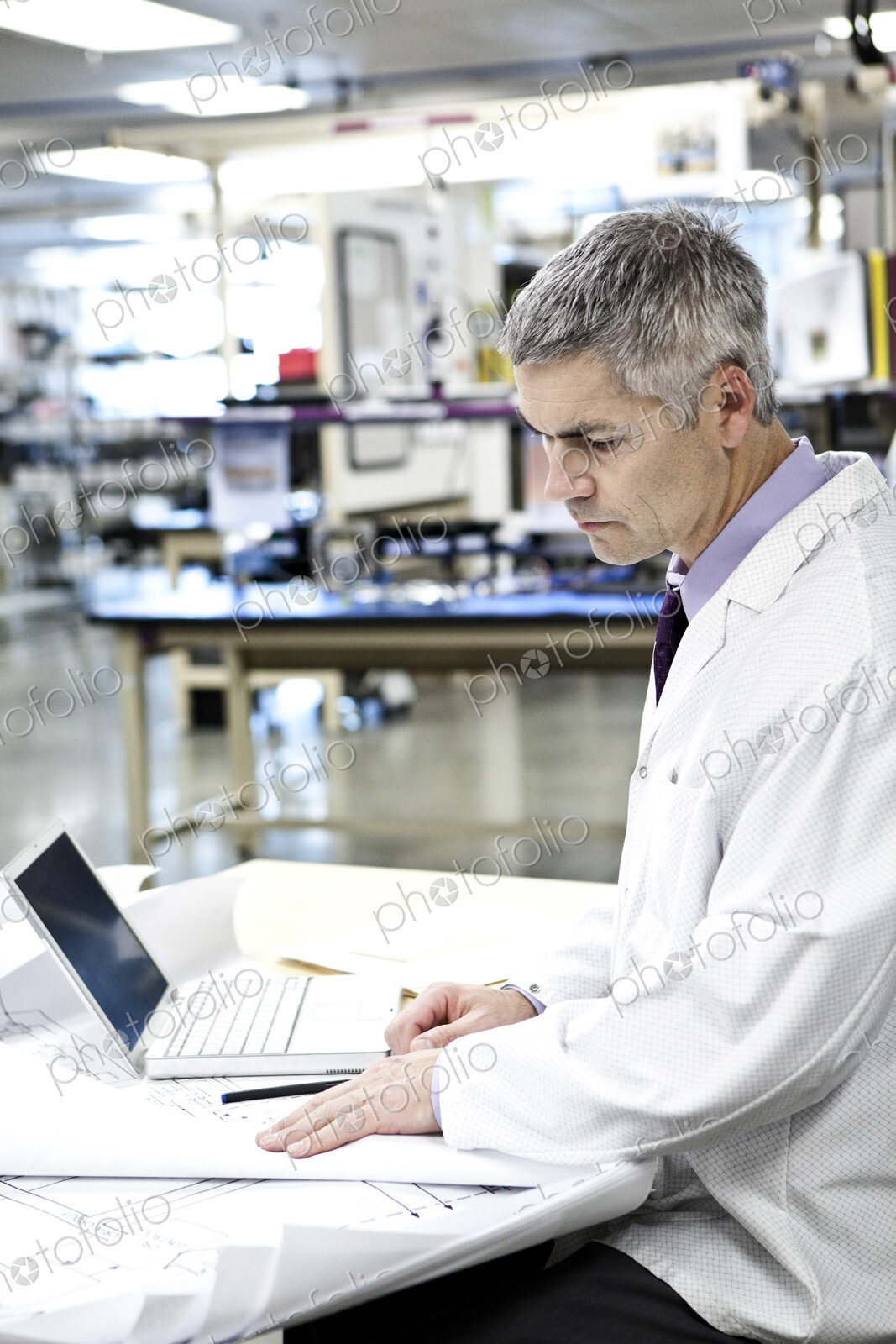 A male caucasian technician in white coat using a laptop computer