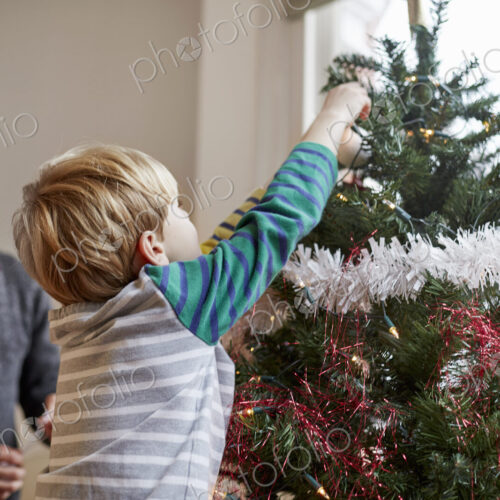 A man and a boy decorating a Christmas Tree together. A man and a boy decorating a Christmas Tree together.