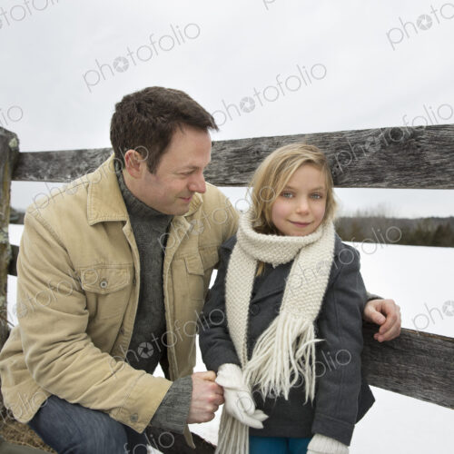 A man and a child leaning on a fence outdoors. A farm in the snow. A man and a child leaning on a fence outdoors. A farm in the snow.