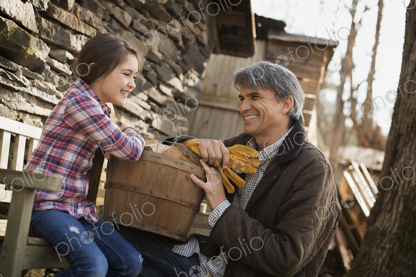 A man and a child on an organic farm. A young girl sitting on a fence, with a wooden…